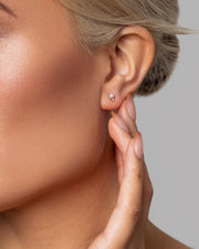 A woman wears 14k Solid Gold stud earrings with freshwater Akoya pearls paired with a diamond