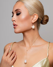Asian woman wears the 0.06ct bezel set topaz and natural Baroque drop pearl earrings