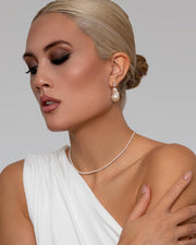 An Asian woman wears the gold stud statement earrings with their glittering AAA grade topaz and lustrous pearl-drop.