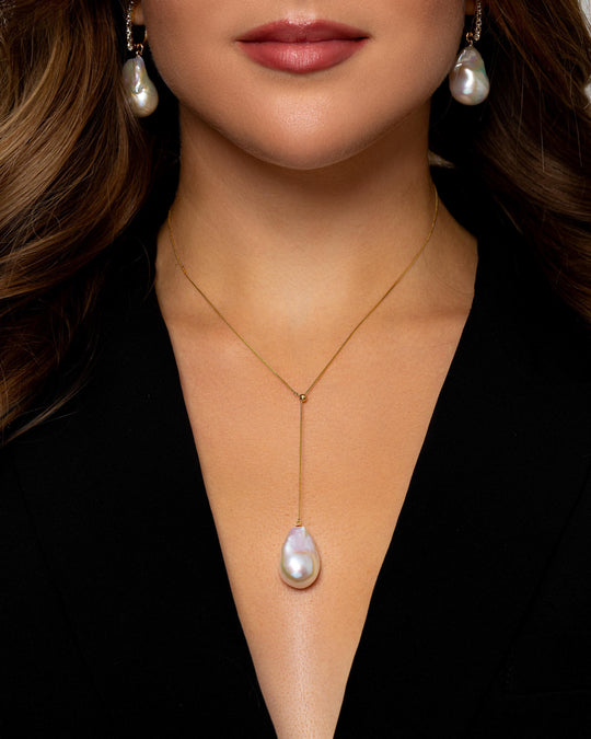 A Caucasian woman wears a 45cm long gold necklace with a large Baroque freshwater pearl