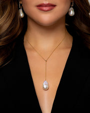 A Caucasian woman wears a 45cm long gold necklace with a large Baroque freshwater pearl